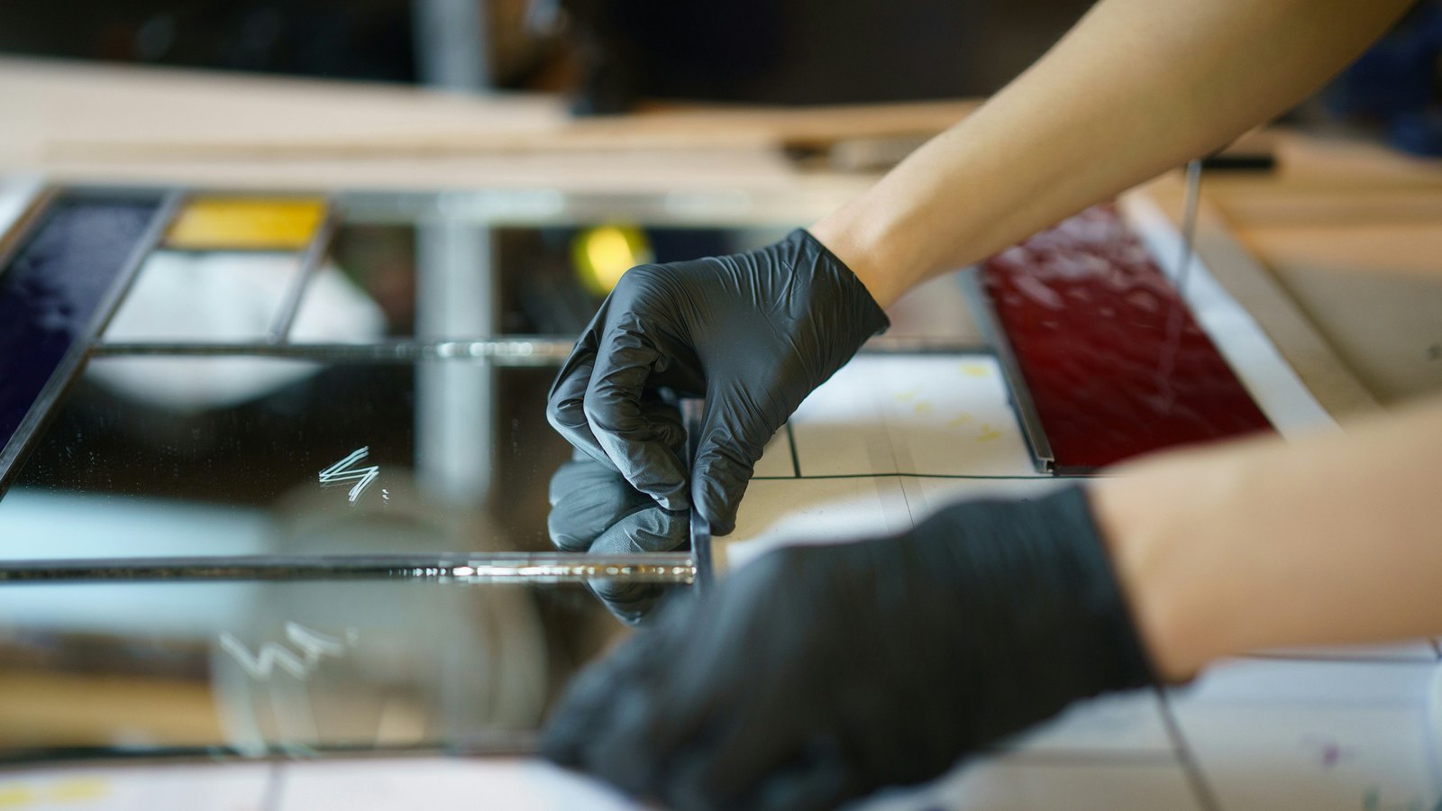 Hands at a workbench cutting and finishing glass