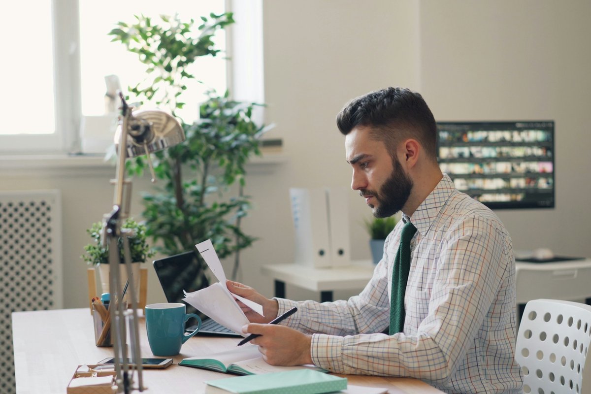 A man sitting at a desk with a laptop and papers