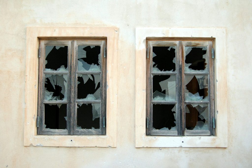 Two broken 6-pane windows on white painted wall