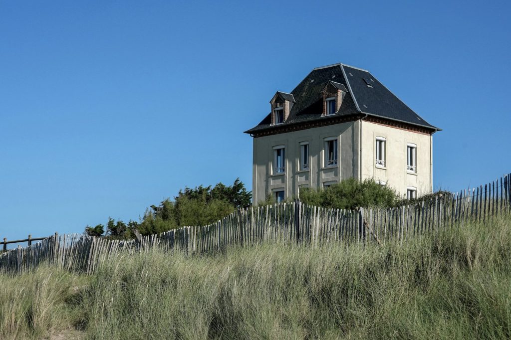 House on a dune behind a wooden fence