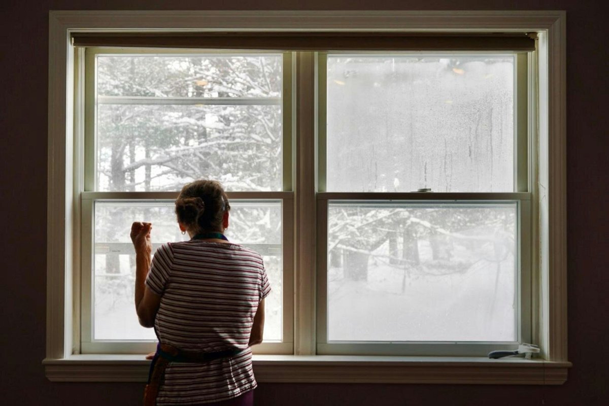 A person looks out a window at the wintery scene.