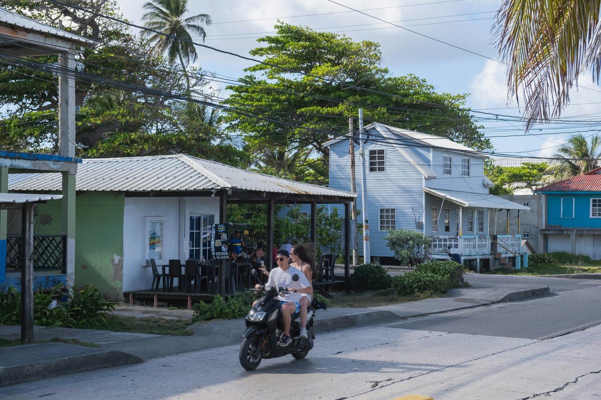 A couple rides a scooter down a street.