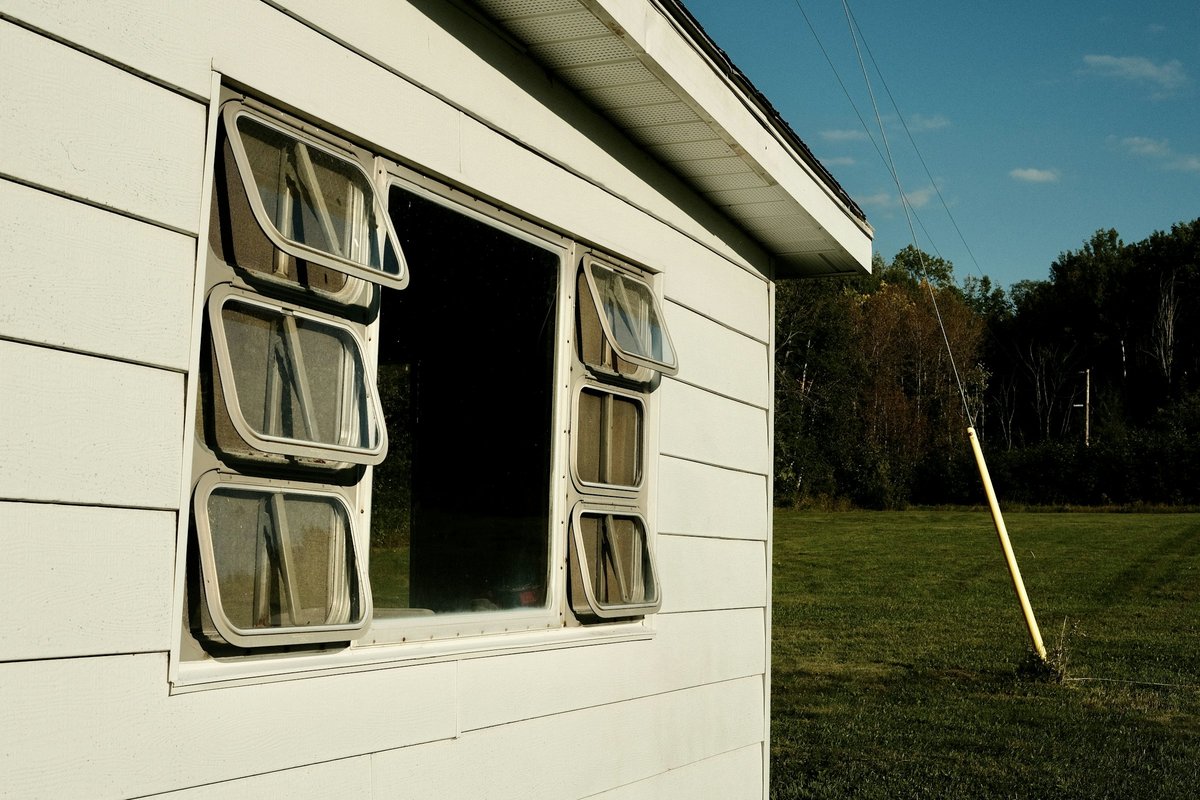 A window on a white house with a green field in the background
