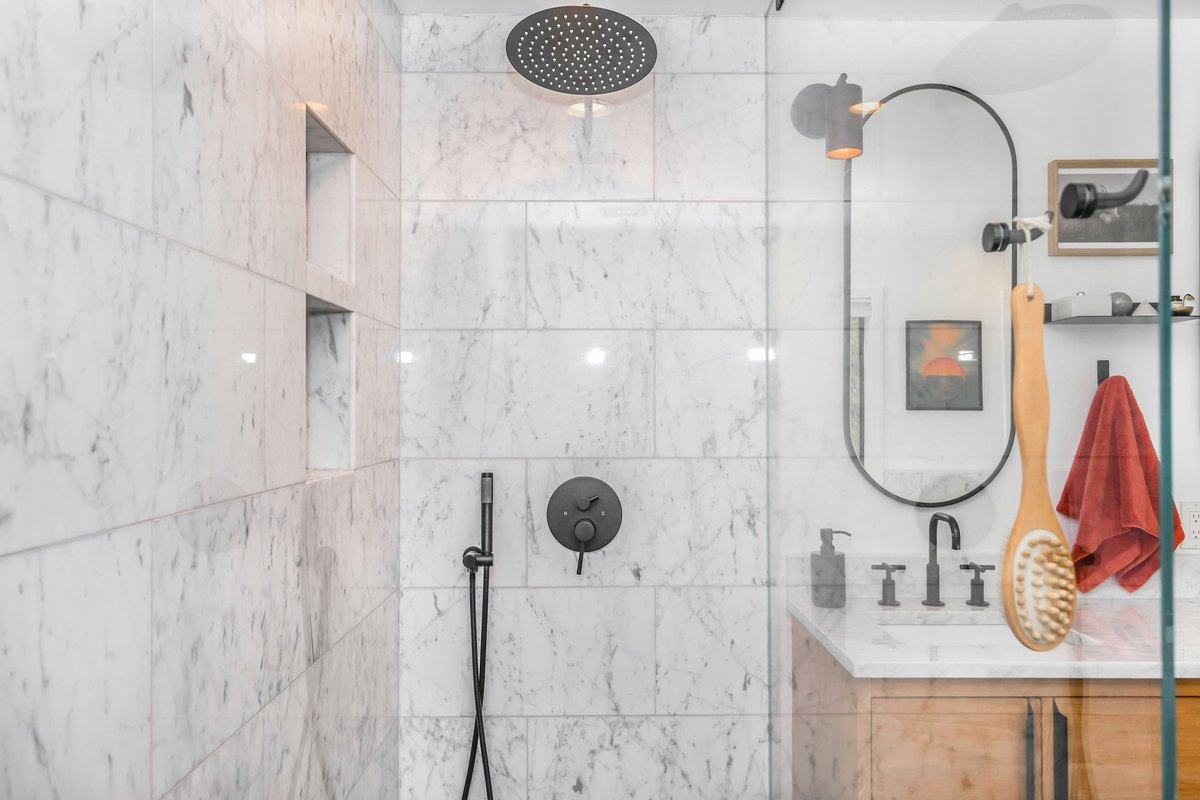 Black shower head on white ceramic wall tiles