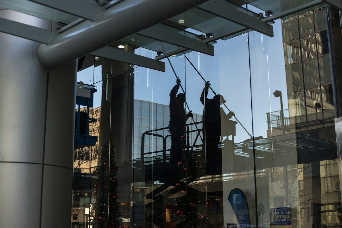 Worker on a scissor platform working on a commercial glass storefront, showing the kind of on-site activity that is usually the shortest part of the project