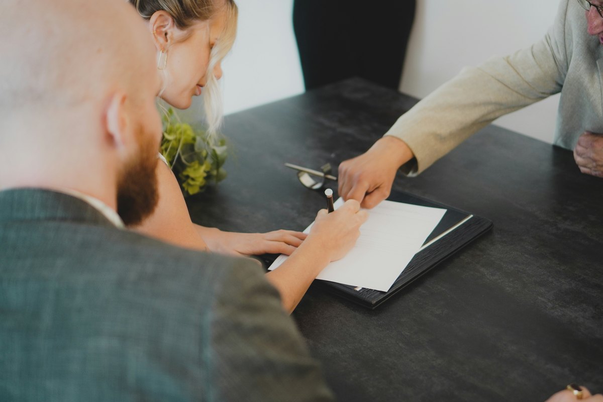 Two people signing a document at a desk, illustrating the importance of reading the contract carefully