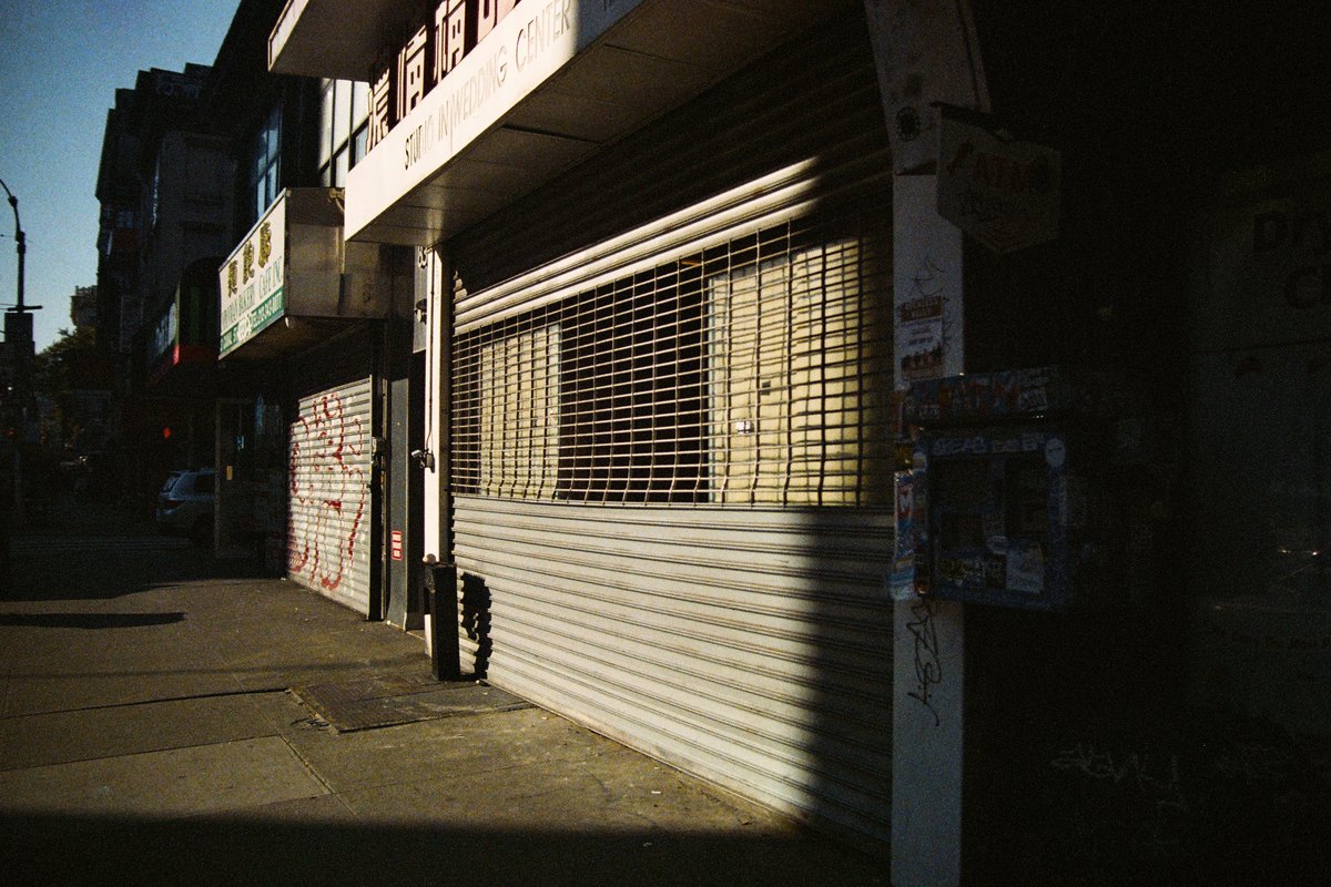 Closed storefront with a metal security shutter rolled down, the classic after-hours security choice for Jamaican retail