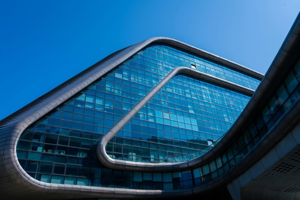 Modern glass building with curved architecture against blue sky